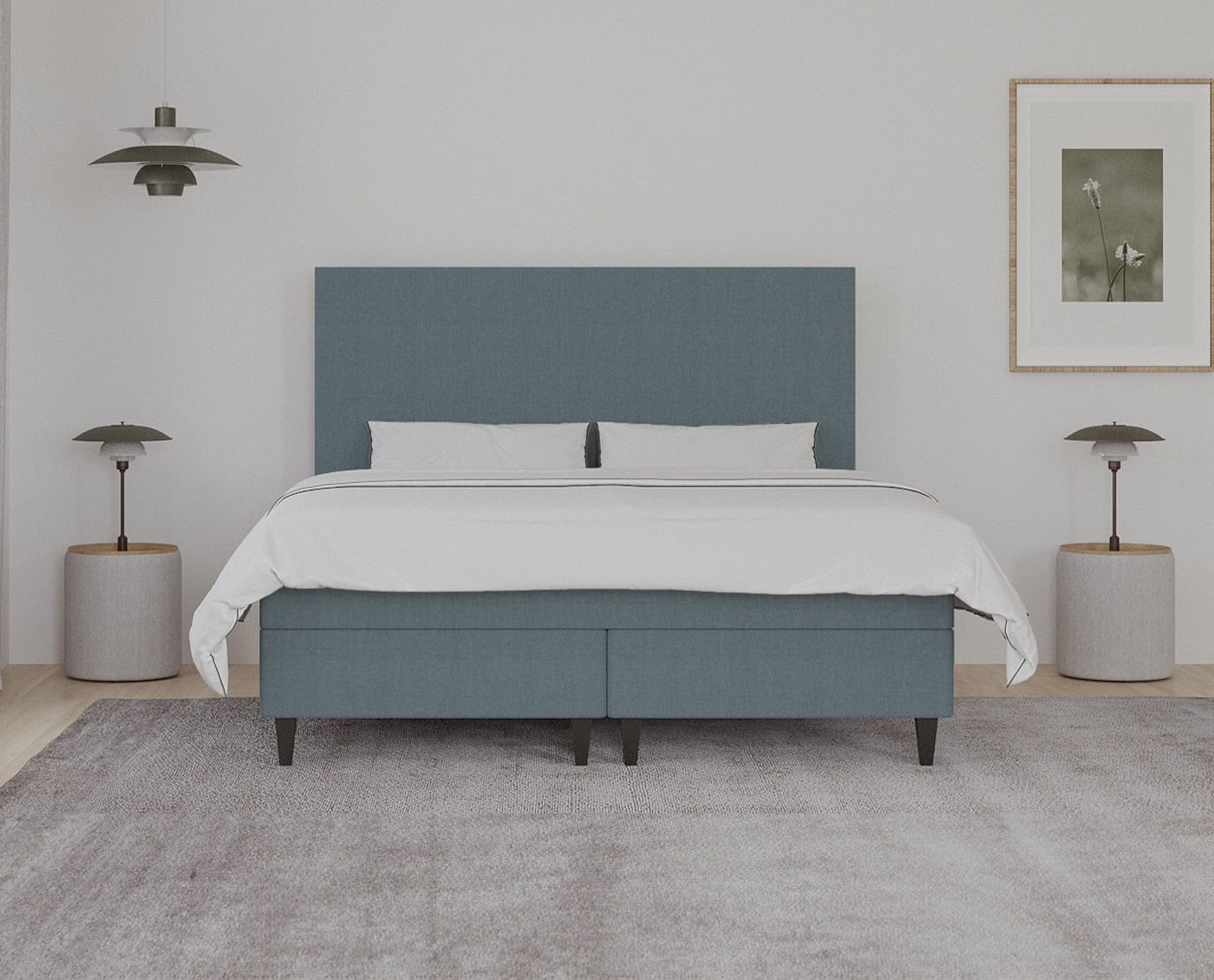 Senge i minimalistisk design med blåpudset front og komfortable dyner, omgivet af moderne natborde og lamper, skaber en afslappende og stilfuld soveværelsesindretning.