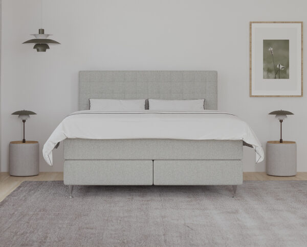 Billed af et moderne og minimalistisk soveværelse med specialfremstillet seng i lyse nuancer, omgivet af elegante boligbelysning og kunst på væggen. Perfekt til en komfortabel og stilfuld soveoplevelse.